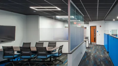 Conference room with glass wall partition and grid square shaped lighting in the ceiling.